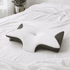 Butterfly-shaped sleep pillow with a white quilted top and charcoal mesh sides resting on a bed.